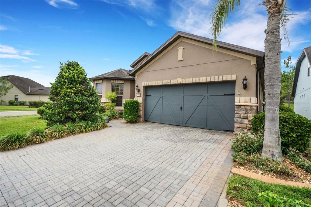 A tan house with a gray garage door and a paved driveway under a blue sky — 100 CASTELLON COURT, DAVENPORT, FL