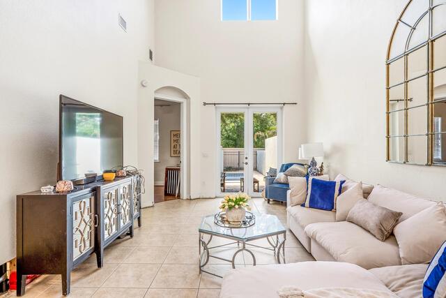 A living room features a large television, a beige sofa, and glass doors to a patio — VERO BEACH, FL