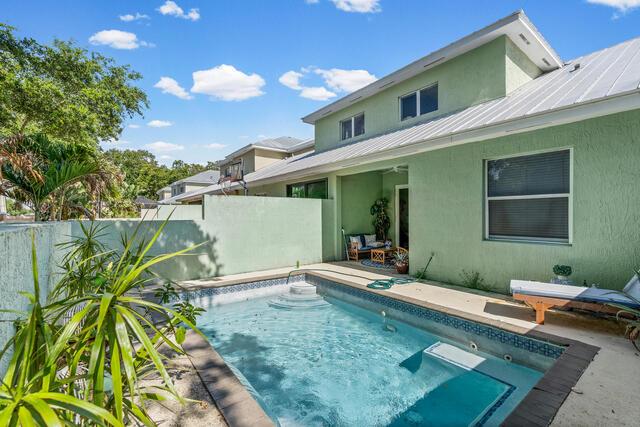 A green house with a metal roof features a small backyard swimming pool and patio — VERO BEACH, FL