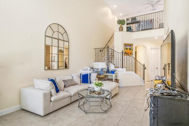 A living room features a white sectional sofa, a glass coffee table, and a staircase — VERO BEACH, FL