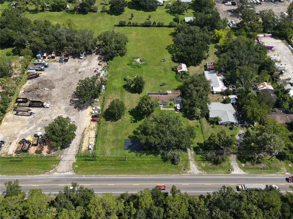 An aerial view shows a large grassy lot with a house, outbuildings, and construction equipment — 6043 S ORANGE BLOSSOM TRAIL, DAVENPORT, FL
