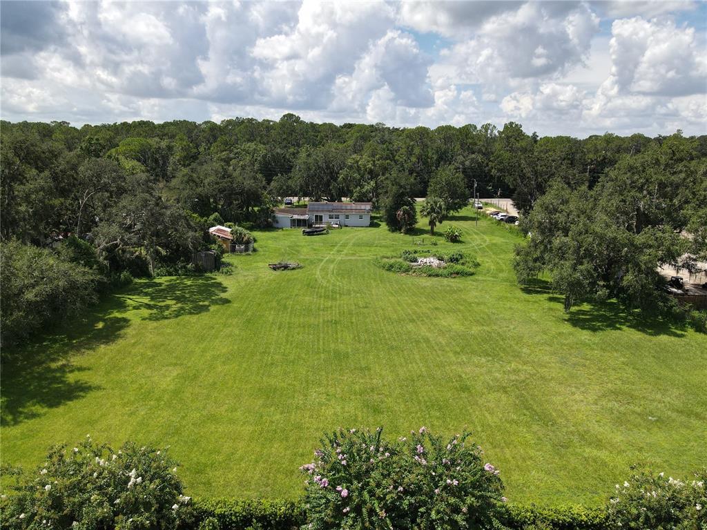 An aerial view shows a house situated on a large, grassy lot surrounded by trees — 6043 S ORANGE BLOSSOM TRAIL, DAVENPORT, FL