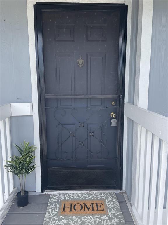A dark gray front door with a decorative metal screen door and a welcome mat — 6033 34TH STREET W UNIT 104, BRADENTON, FL