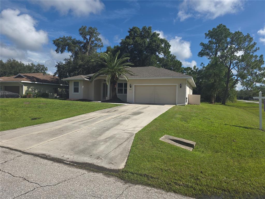 A single-story house with a beige exterior, a two-car garage, and a palm tree — 4038 LANGSOM LANE, NORTH PORT, FL