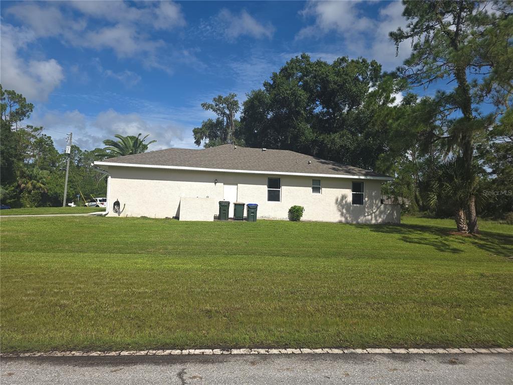 A side view of a single-story stucco house with a shingled roof and lawn — 4038 LANGSOM LANE, NORTH PORT, FL