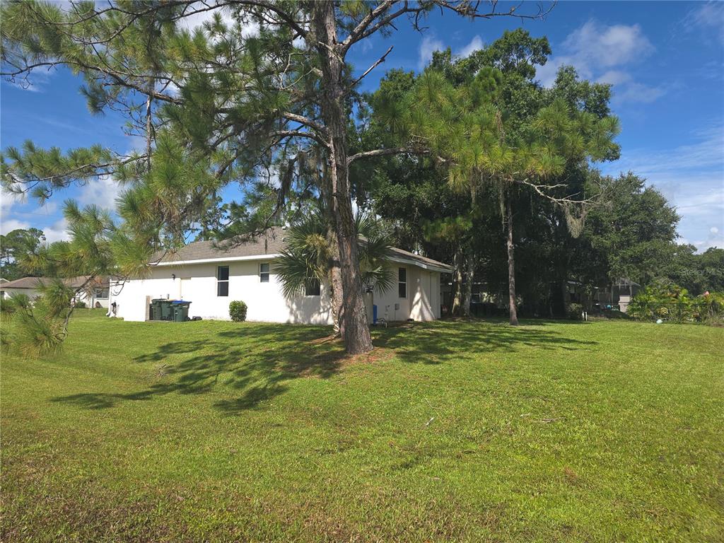 A white house with a hip roof sits on a large, grassy lot with trees — 4038 LANGSOM LANE, NORTH PORT, FL