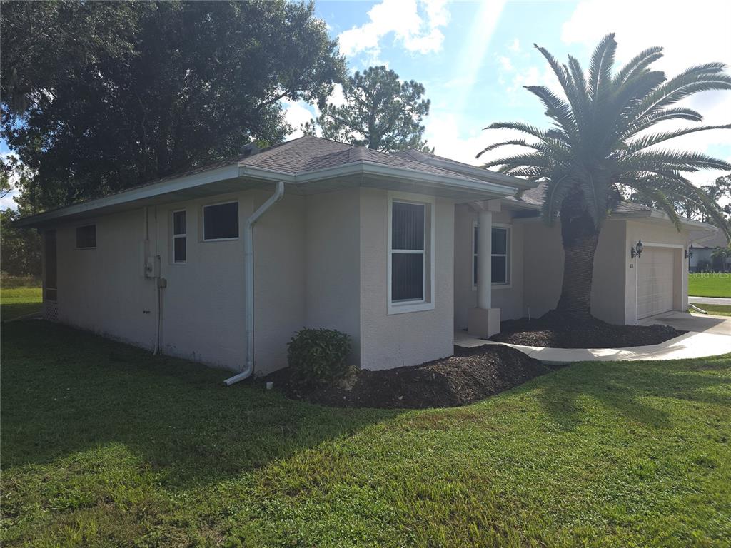 A single-story house with light-colored stucco siding, a palm tree, and an attached garage — 4038 LANGSOM LANE, NORTH PORT, FL
