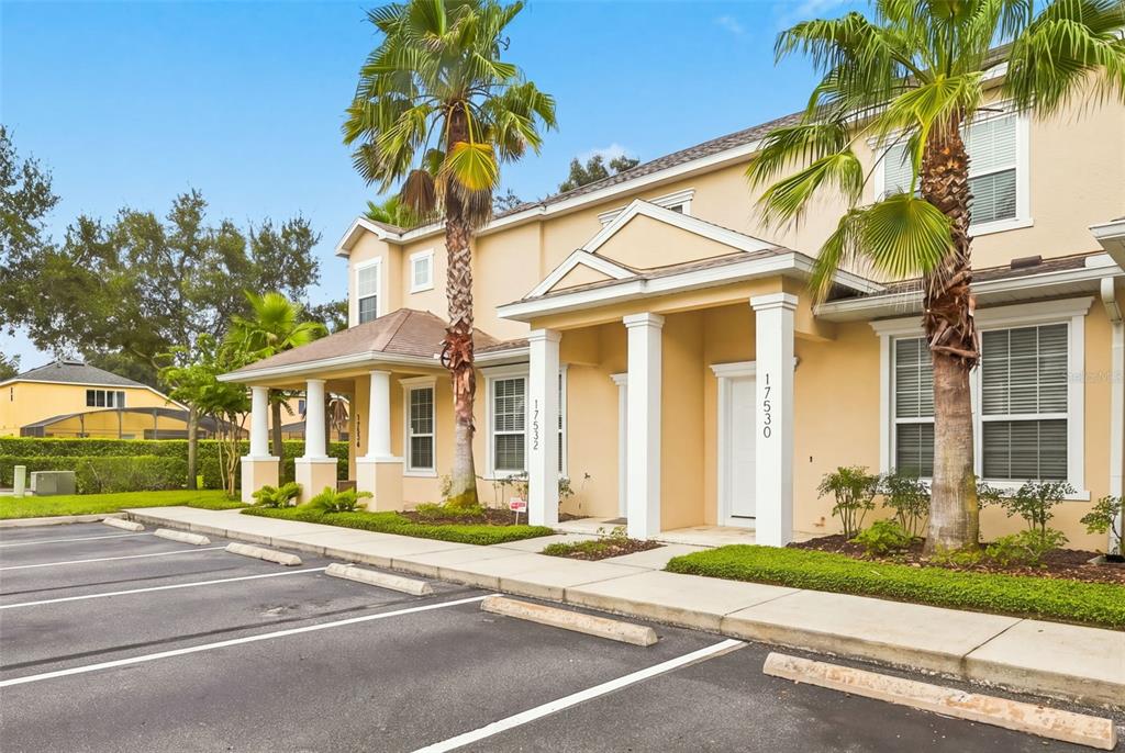 A two-story tan stucco townhouse with white columns and palm trees in front — 17530 PLACIDITY AVENUE, CLERMONT, FL