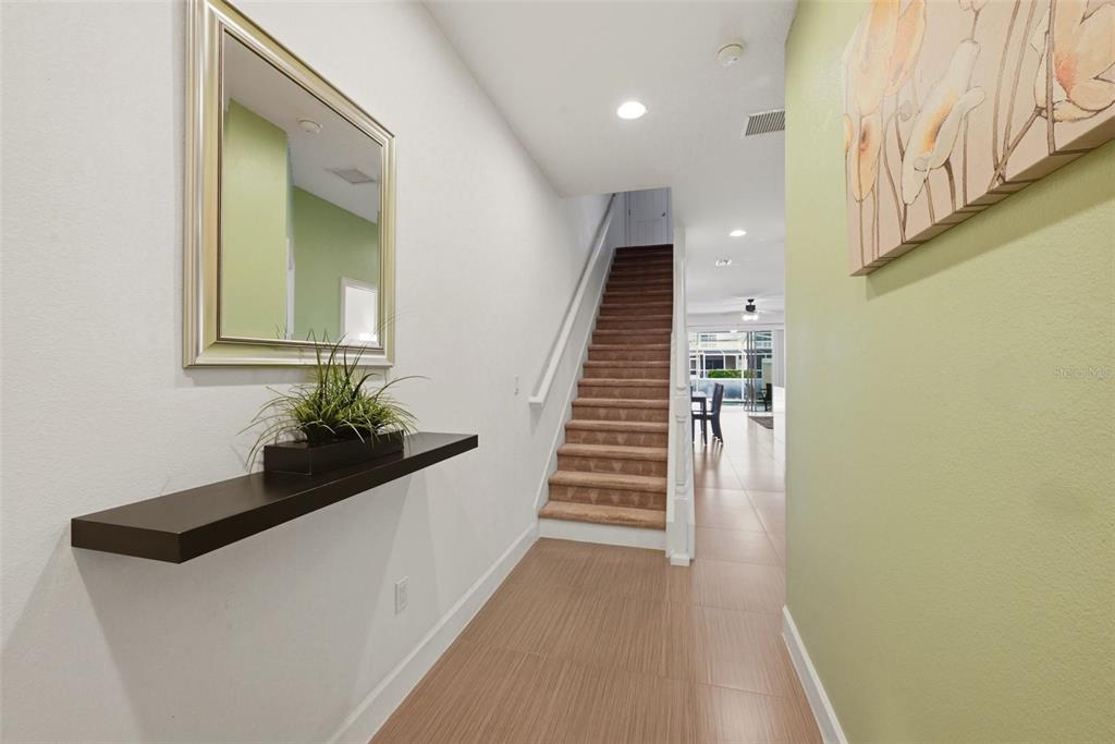 A bright entryway features a floating shelf, a wall mirror, and stairs leading to the second floor — 17530 PLACIDITY AVENUE, CLERMONT, FL
