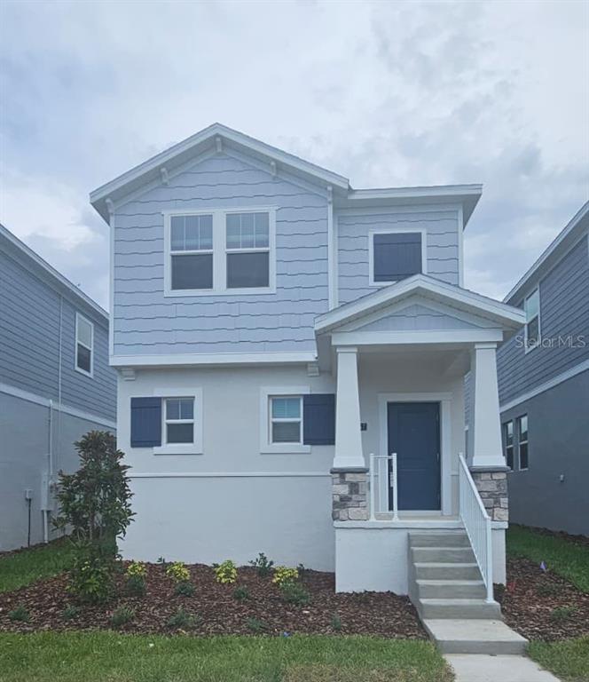 A two-story house features light blue siding, a covered front porch, and a concrete staircase — 2557 RIDER RAIN LANE, APOPKA, FL