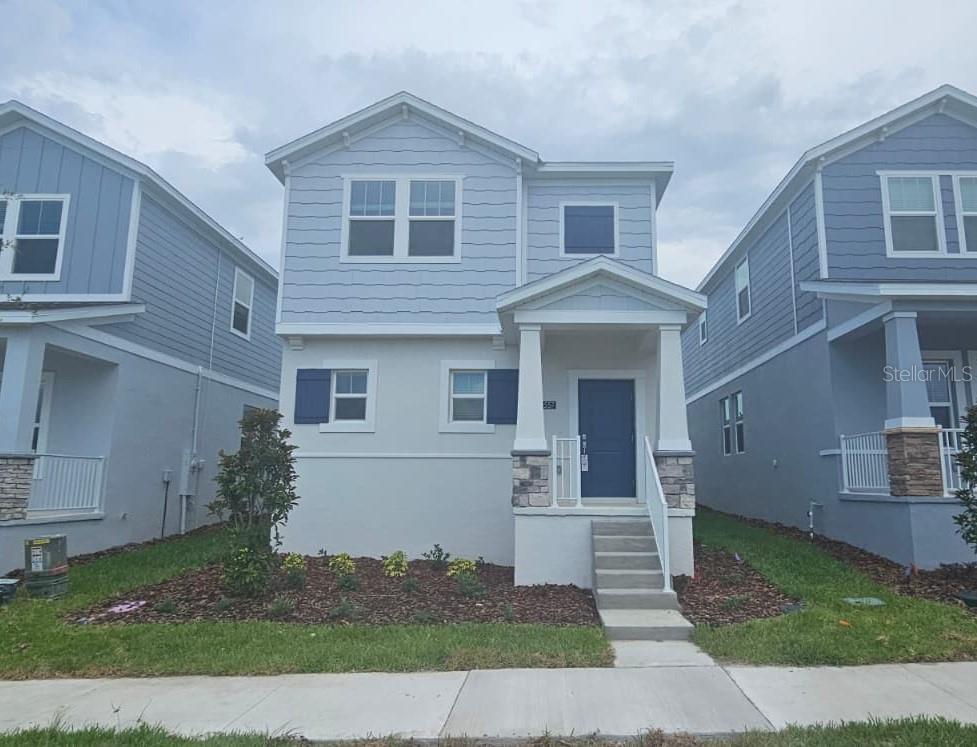 A two-story house with light blue siding, a covered front porch, and stone accents — 2557 RIDER RAIN LANE, APOPKA, FL