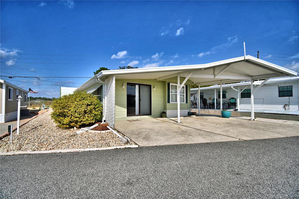 A light green mobile home features a concrete carport and a gravel front yard — 251 PATTERSON ROAD UNIT A22, HAINES CITY, FL