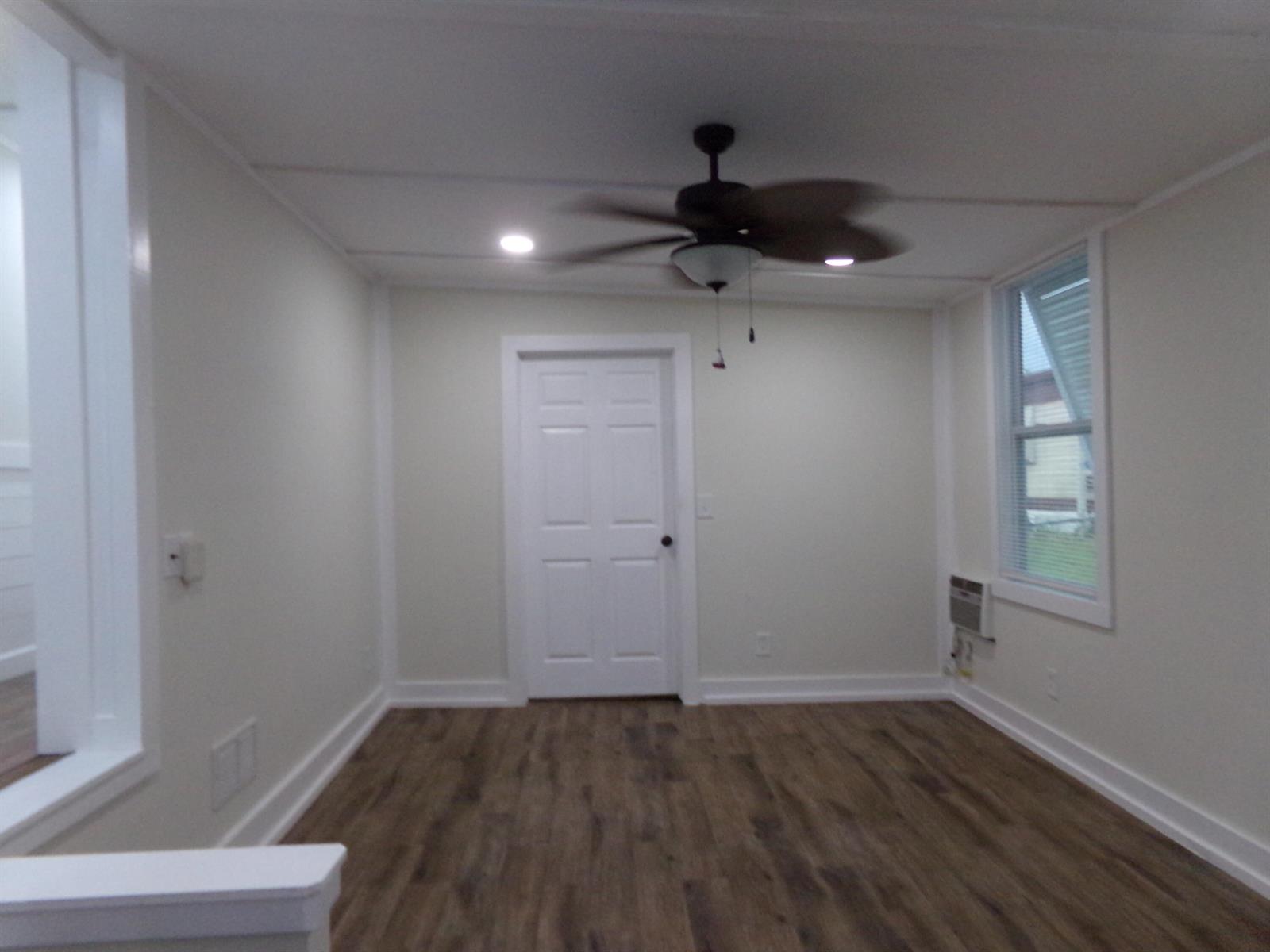 An empty room features light-colored walls, wood-look flooring, a ceiling fan, and a white door — 59005 Captiva Bay, Boynton Beach FL 33436, BOYNTON BEACH, FL