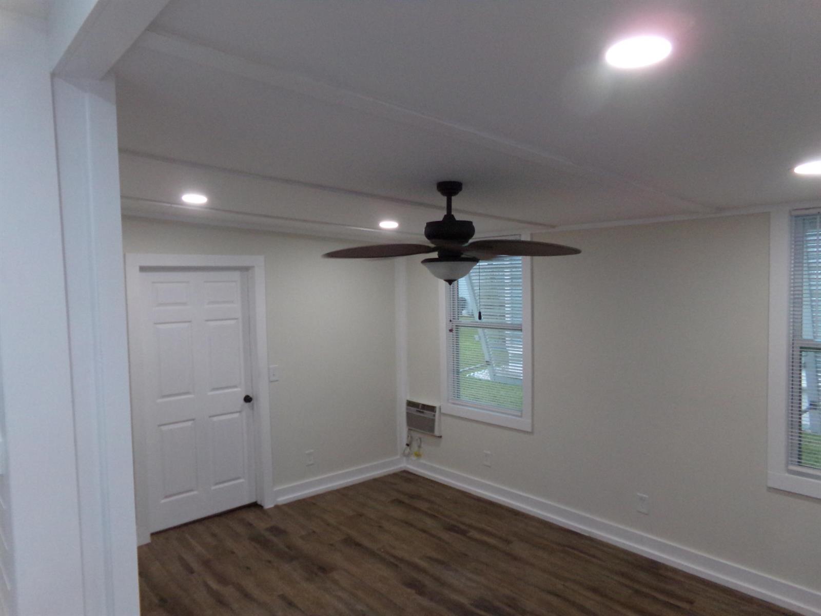 An empty room features white walls, wood-look flooring, a ceiling fan, and two windows — 59005 Captiva Bay, Boynton Beach FL 33436, BOYNTON BEACH, FL