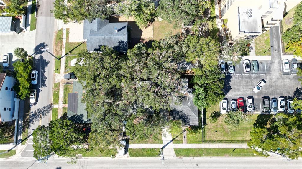 An aerial view shows a house surrounded by large trees next to a parking lot — 711 N ORANGE AVENUE, SARASOTA, FL