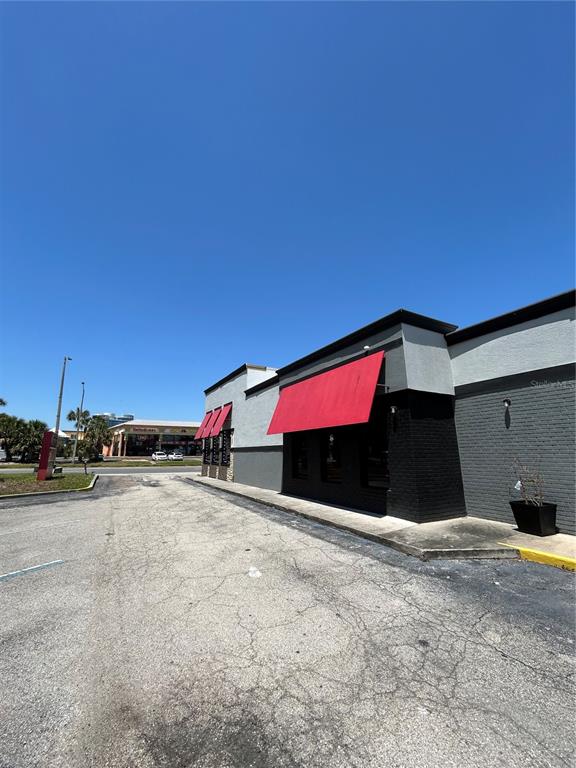 The exterior of a commercial building features gray brick walls and red fabric awnings — 6320 INTERNATIONAL DRIVE, ORLANDO, FL