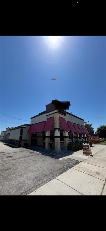 A low-angle exterior view of a commercial building with red awnings and stone accents — 6320 INTERNATIONAL DRIVE, ORLANDO, FL