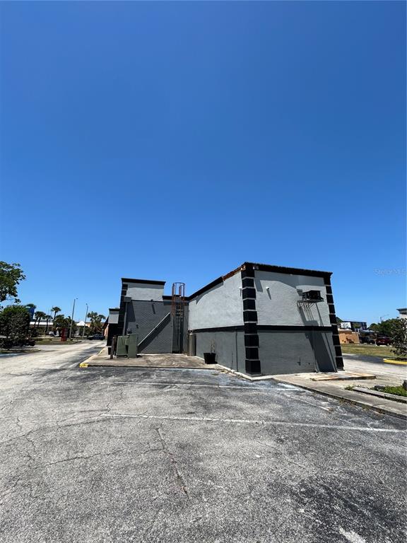 The exterior of a commercial building features a gray stucco facade and a metal ladder — 6320 INTERNATIONAL DRIVE, ORLANDO, FL