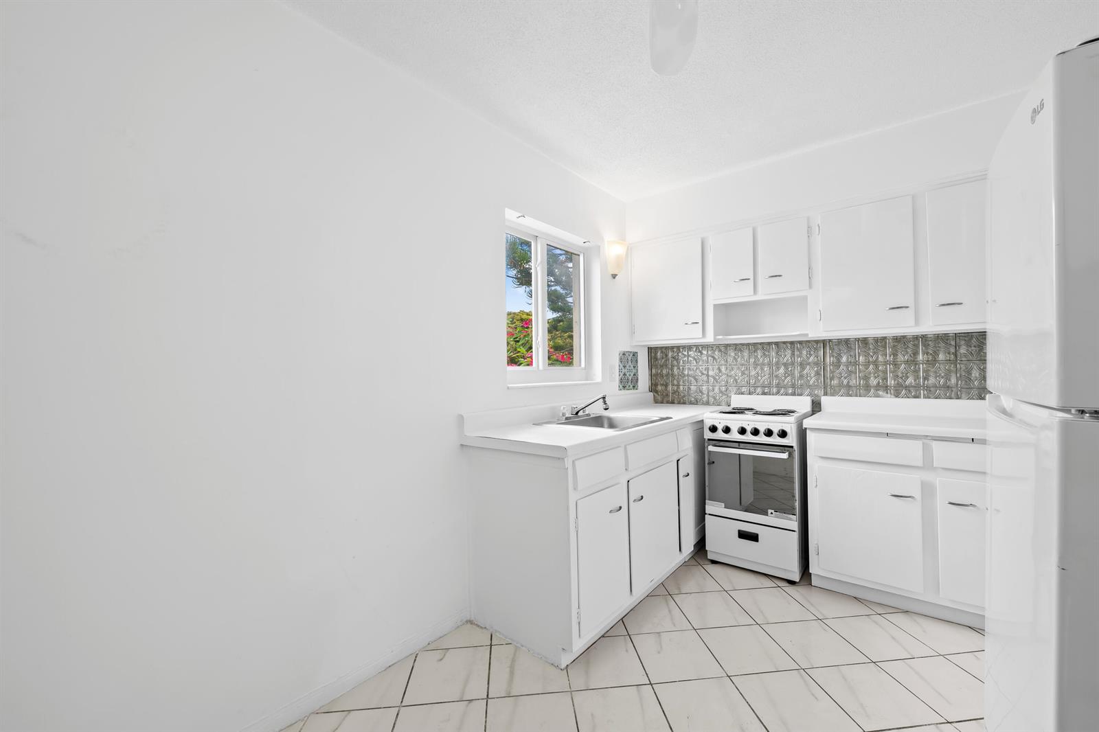 A white kitchen features a sink, a gas stove, and a patterned metal backsplash — 2601 NE 1st Street # 17, Pompano Beach FL 33062, POMPANO BEACH, FL