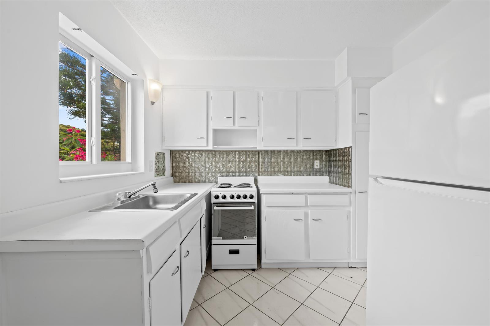 A kitchen with white cabinets, a white stove, a metal backsplash, and a window — 2601 NE 1st Street # 17, Pompano Beach FL 33062, POMPANO BEACH, FL