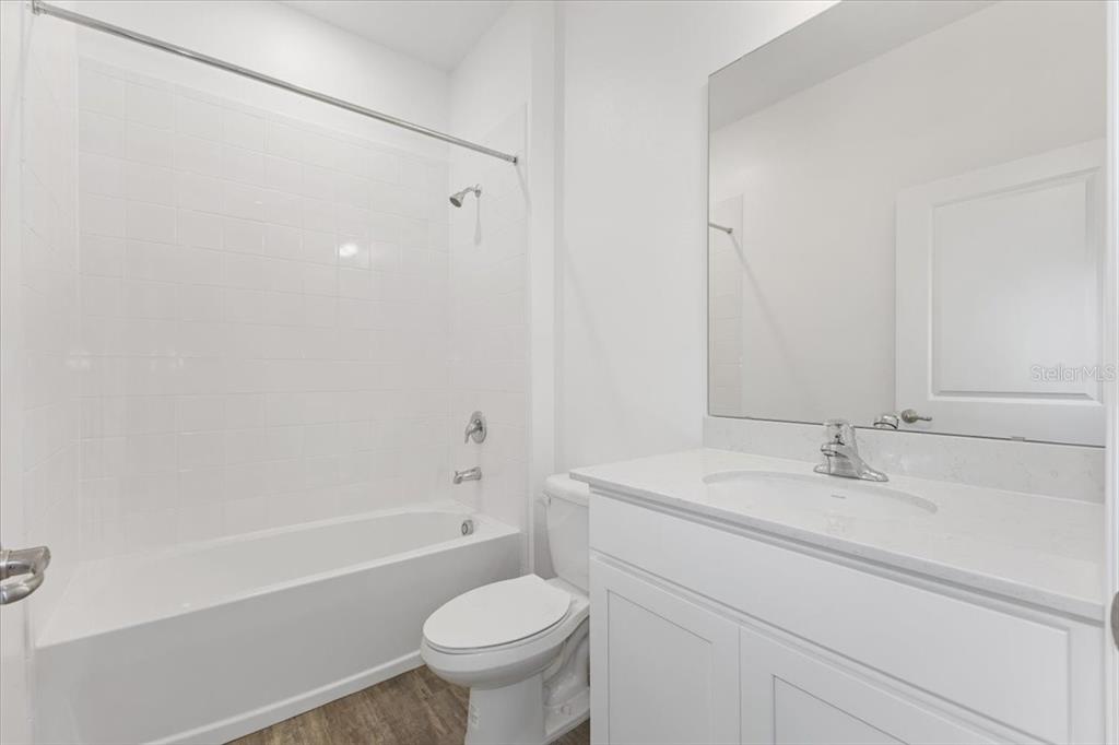 A bathroom features a white vanity, a toilet, and a shower-tub combination with white tiles — 2257 SIRENA LANE, MOUNT DORA, FL