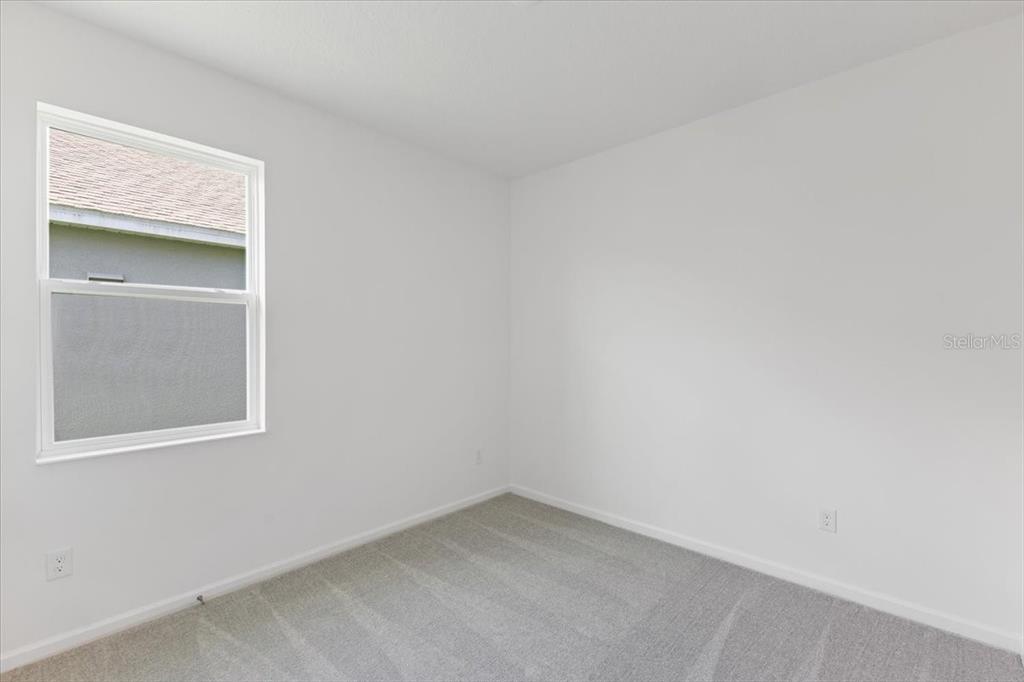 An empty bedroom features white walls, gray carpeting, and a single window — 2257 SIRENA LANE, MOUNT DORA, FL