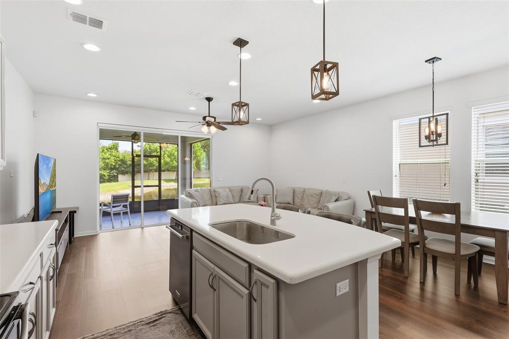 A kitchen island with a sink overlooks an open-concept living and dining area — 141 MITCHELL CREEK WAY, OVIEDO, FL