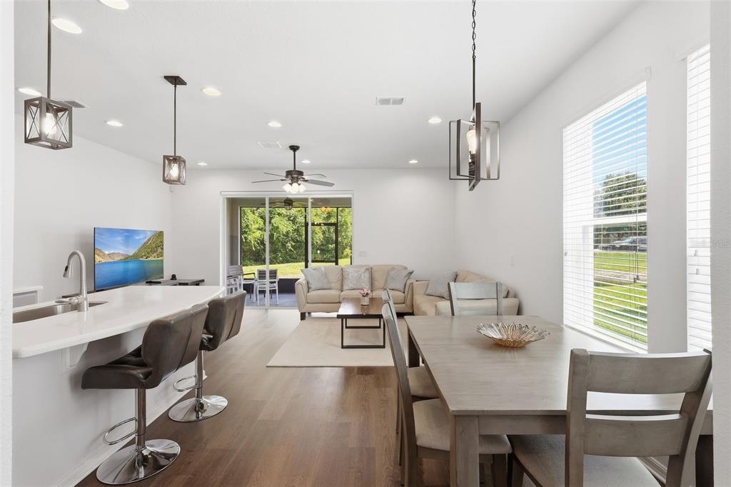 An open-concept living area features a kitchen island, dining table, and a rear patio view — 141 MITCHELL CREEK WAY, OVIEDO, FL
