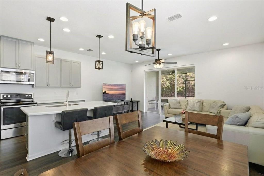 An open-concept kitchen, dining area, and living room with light cabinetry and wood-toned furniture — 141 MITCHELL CREEK WAY, OVIEDO, FL