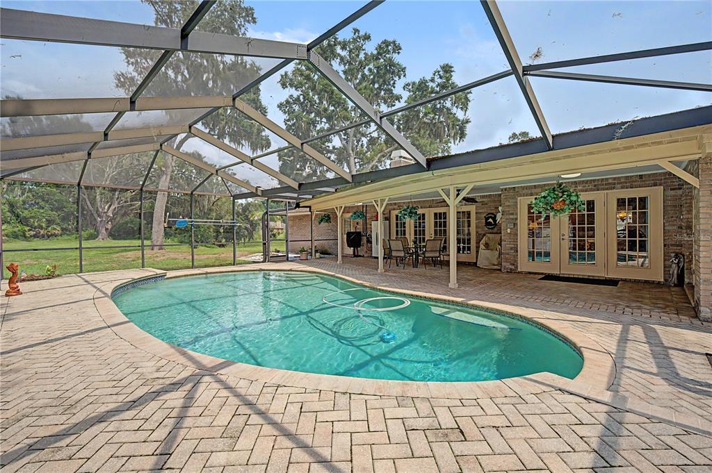 A screened-in patio features a swimming pool and brick pavers under a covered porch — 3901 BUTTONWOOD COURT, BRANDON, FL