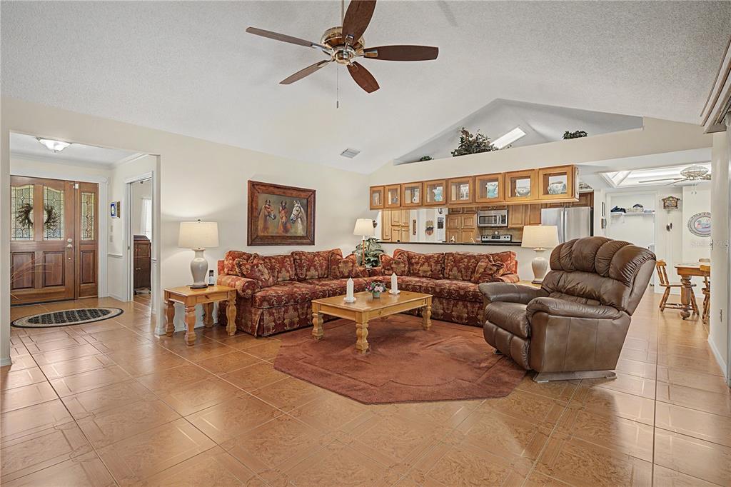 A living room with tile floors, a sectional sofa, a recliner, and an open kitchen — 3901 BUTTONWOOD COURT, BRANDON, FL