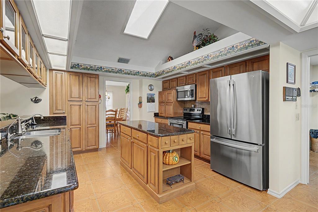 A kitchen with wood cabinets, dark granite countertops, stainless steel appliances, and a central island — 3901 BUTTONWOOD COURT, BRANDON, FL