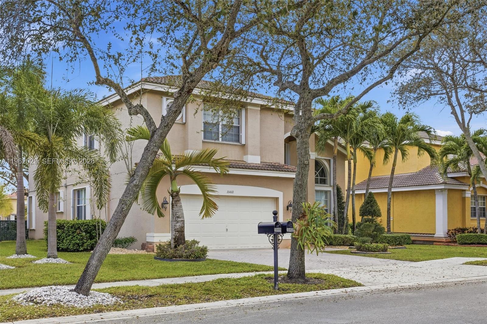 A two-story beige house with a two-car garage and palm trees in the front yard — 16460 SW 30th Street, Miramar FL 33027, MIRAMAR, FL