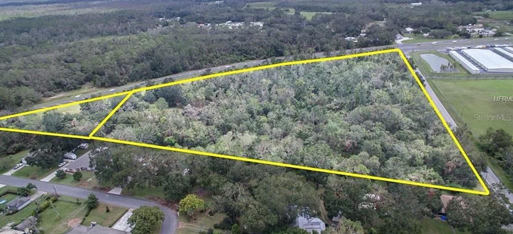 An aerial view shows a large, triangular, wooded plot of land outlined in yellow — 9232 US HIGHWAY 98 N, LAKELAND, FL