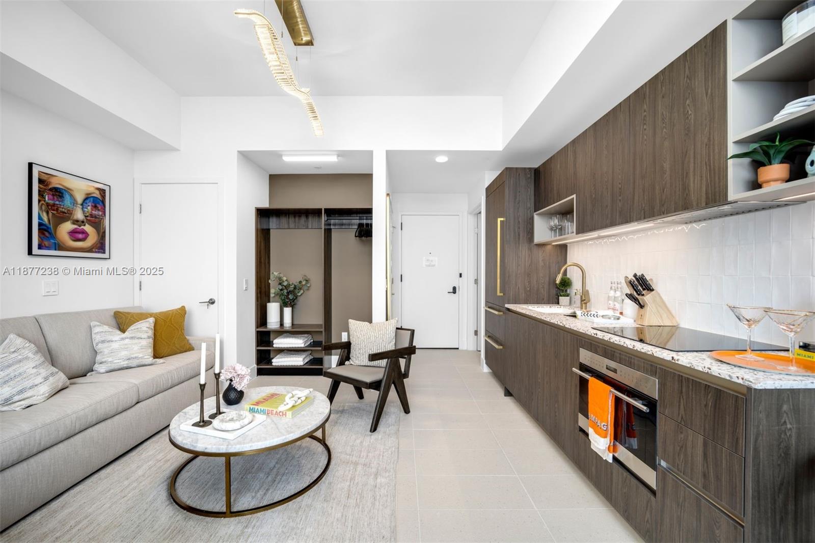 A modern studio apartment features a kitchenette with dark wood cabinetry and a living area — 159 NE 6th St # 5112, Miami FL 33132, MIAMI, FL