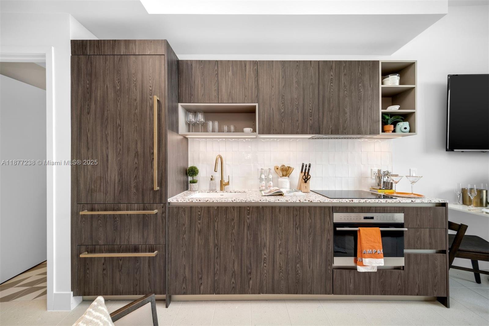 A modern kitchen features dark wood cabinetry, a speckled countertop, and gold-toned hardware — 159 NE 6th St # 5112, Miami FL 33132, MIAMI, FL