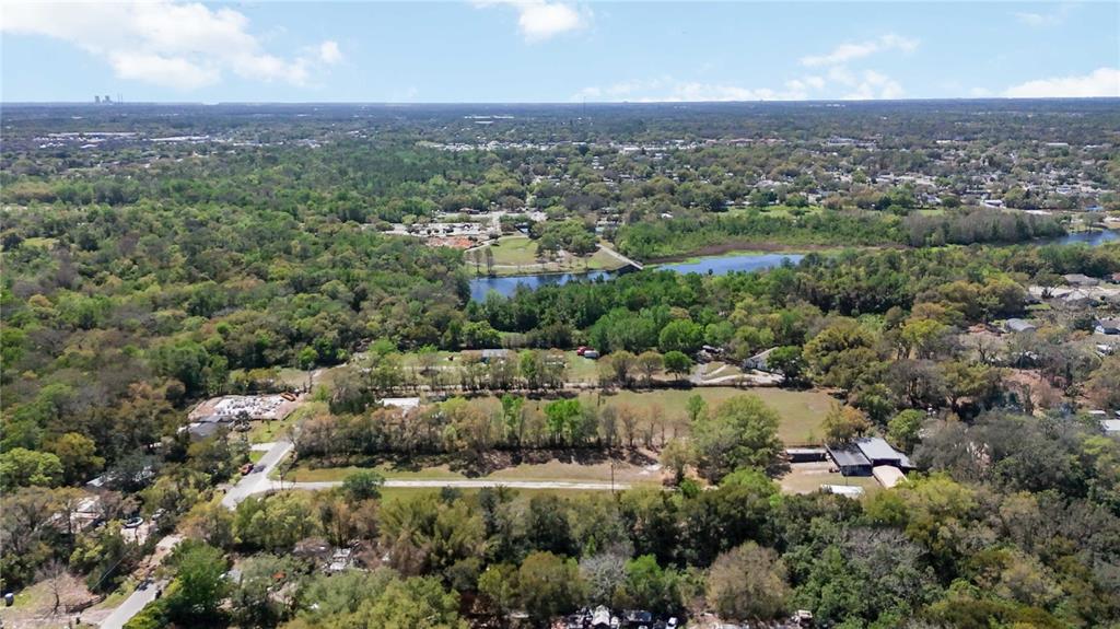 An aerial view shows a large, grassy lot surrounded by dense trees and a nearby pond — 2700 AEIN ROAD, ORLANDO, FL