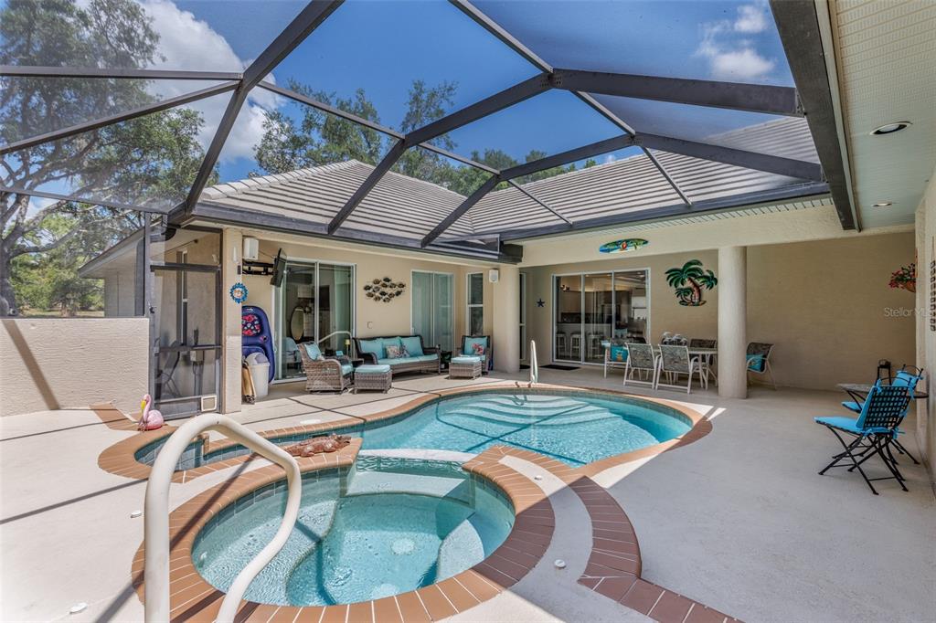 A screened-in patio features a swimming pool, a hot tub, and outdoor seating furniture — 3099 N BARTON CREEK CIRCLE, LECANTO, FL