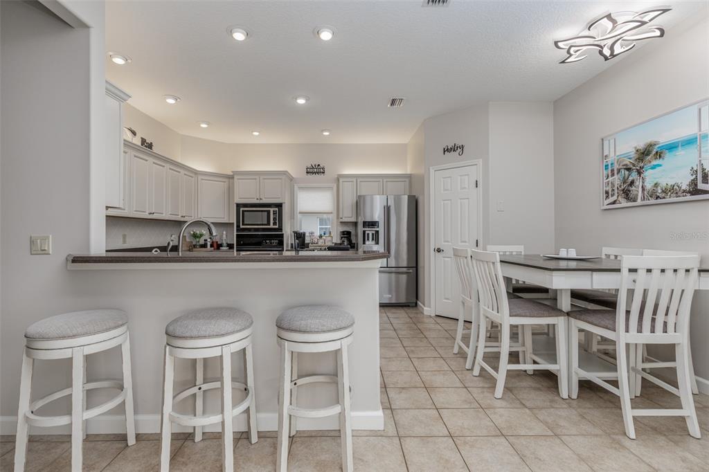 A kitchen with white cabinets, stainless steel appliances, and a dining area with four chairs — 3099 N BARTON CREEK CIRCLE, LECANTO, FL