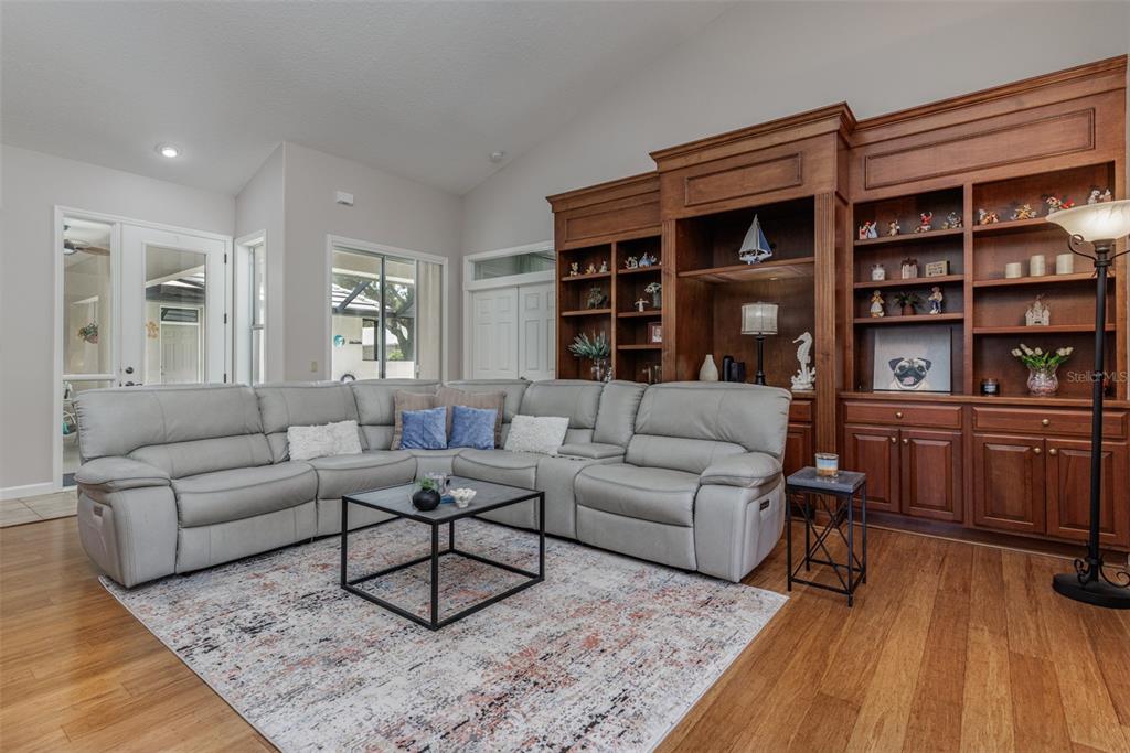 A living room features a grey sectional sofa, a coffee table, and a large wooden bookcase — 3099 N BARTON CREEK CIRCLE, LECANTO, FL