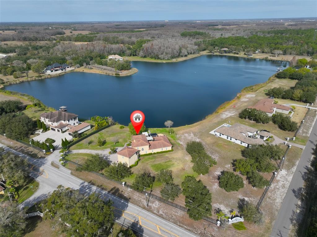 An aerial view shows a house with a red location pin beside a large lake — 10517 TARPON SPRINGS ROAD, ODESSA, FL