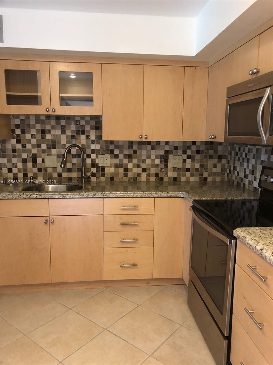 A kitchen features light wood cabinets, granite countertops, a mosaic tile backsplash, and stainless appliances — 4000 N Hills Dr # 32, Hollywood FL 33021, HOLLYWOOD, FL