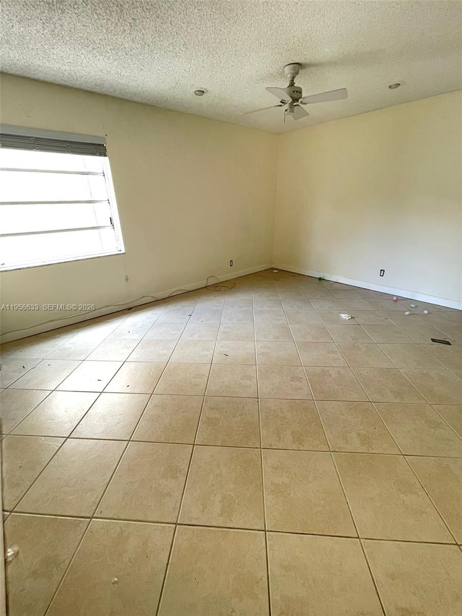 An empty room features beige tile flooring, off-white walls, and a ceiling fan — 4000 N Hills Dr # 32, Hollywood FL 33021, HOLLYWOOD, FL
