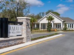 A stone monument sign for Amavi by Mill Creek stands before a modern community clubhouse — 4519 TRINITY WAY UNIT THC2, KISSIMMEE, FL