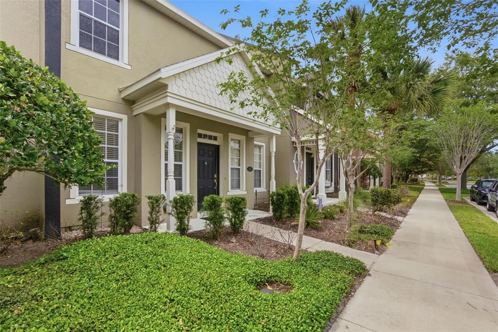 A tan townhouse exterior features a covered entryway, white trim, and a sidewalk out front — 224 WOODHOUSE LANE, DELAND, FL