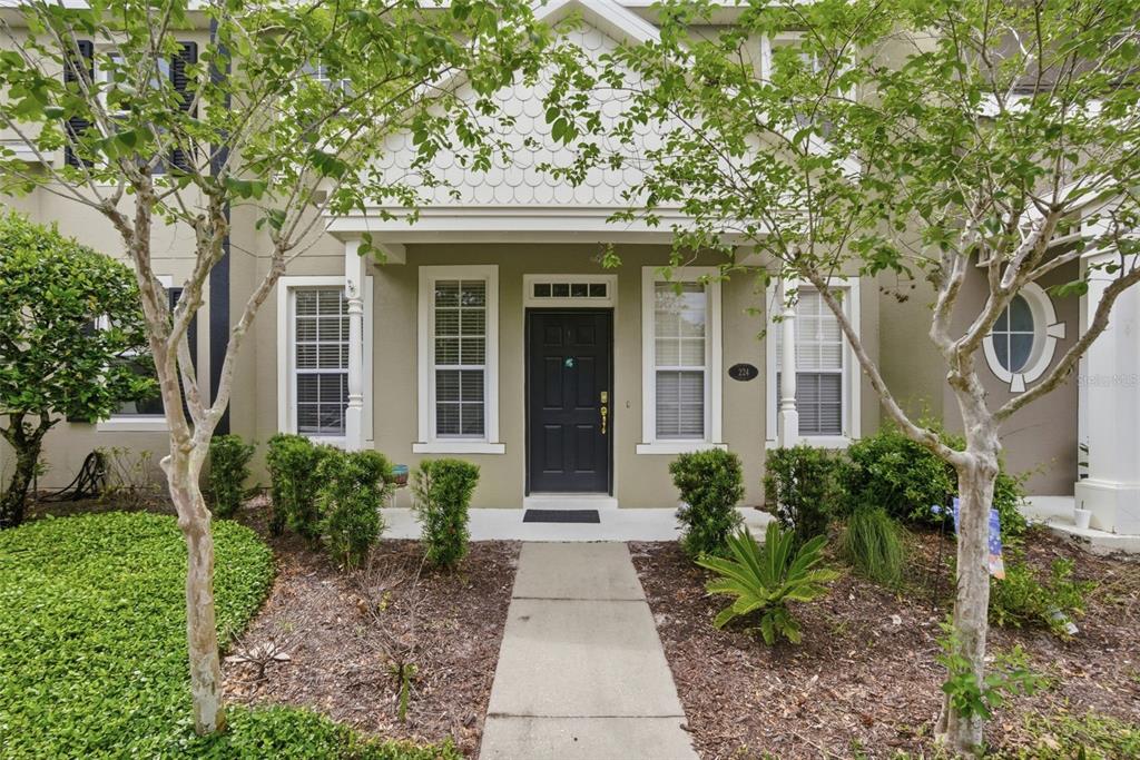 A front exterior view of a two-story townhouse with a dark door and small porch — 224 WOODHOUSE LANE, DELAND, FL