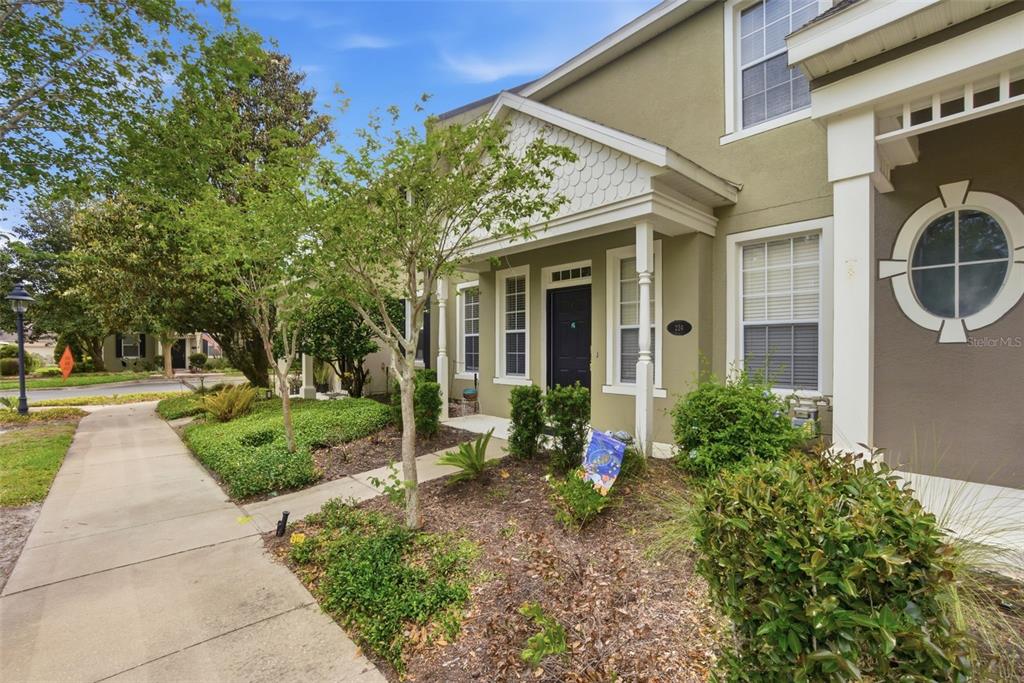 A two-story townhouse with a tan stucco exterior, a covered front porch, and landscaping — 224 WOODHOUSE LANE, DELAND, FL