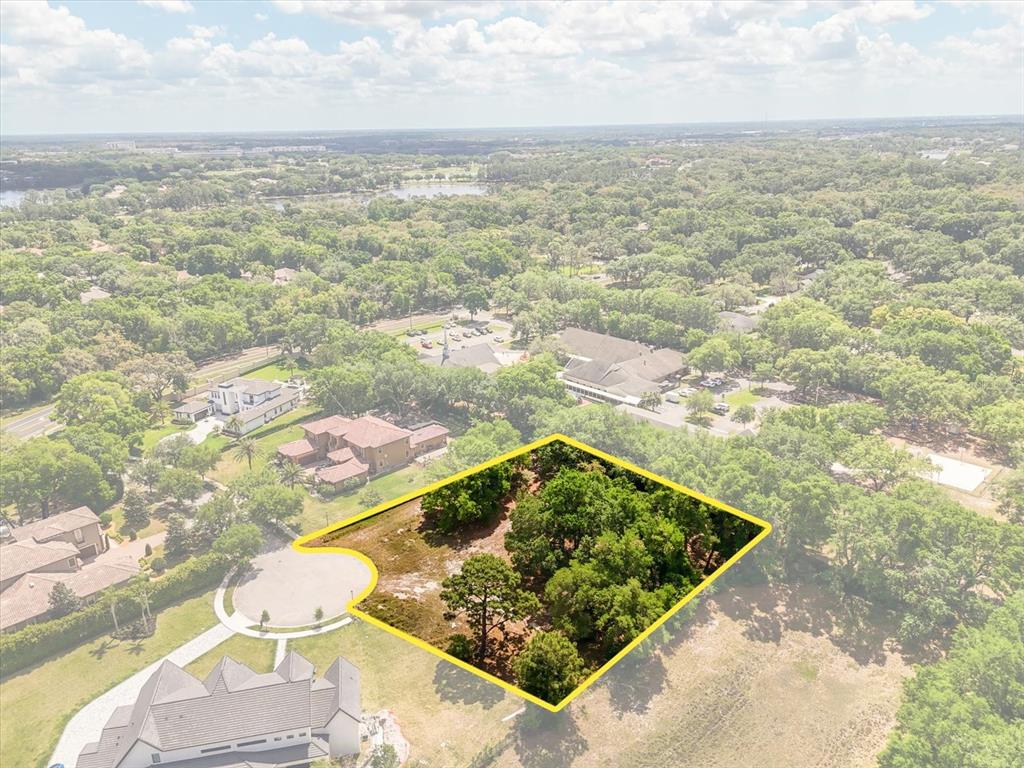 An aerial view shows a vacant, tree-covered residential lot outlined in yellow at a cul-de-sac — 1657 ENCLAVE COVE, LAKE MARY, FL