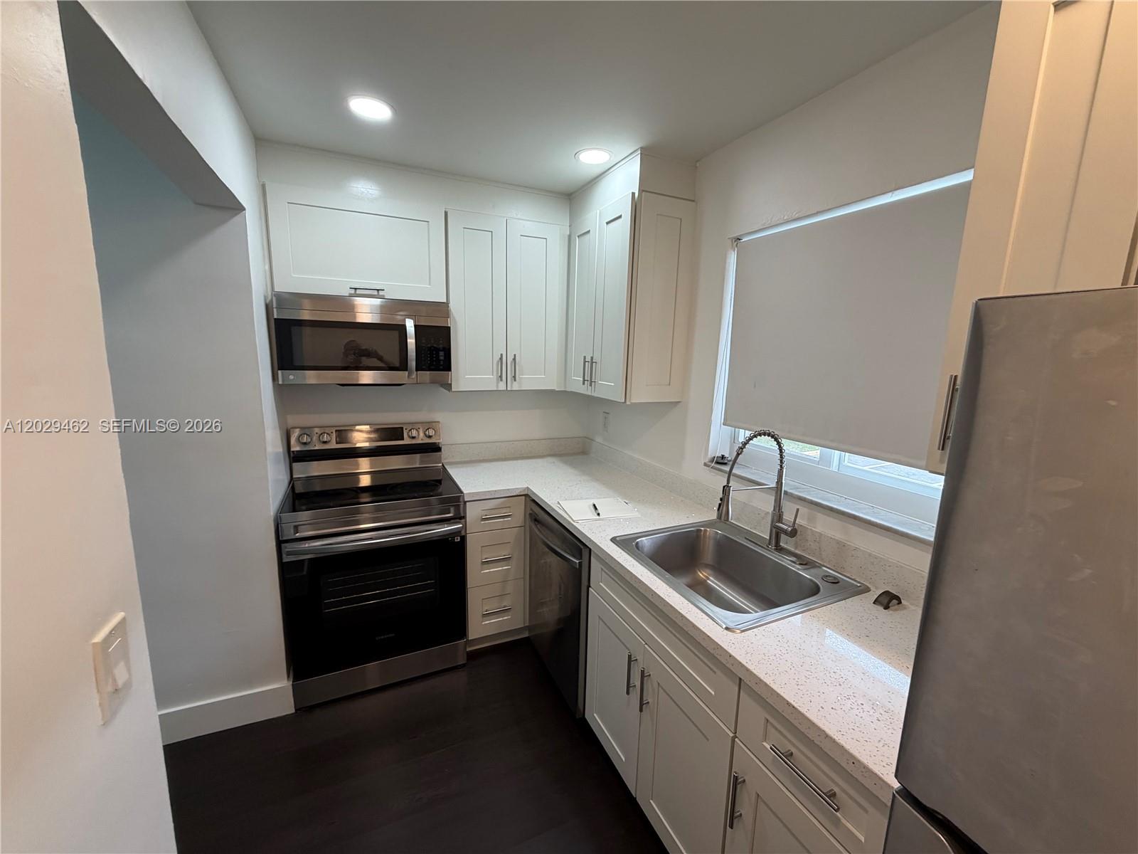 A kitchen features white cabinets, stainless steel appliances, and light-colored speckled countertops — 4850 SW 26th Ave # 4, Dania Beach FL 33312, DANIA BEACH, FL