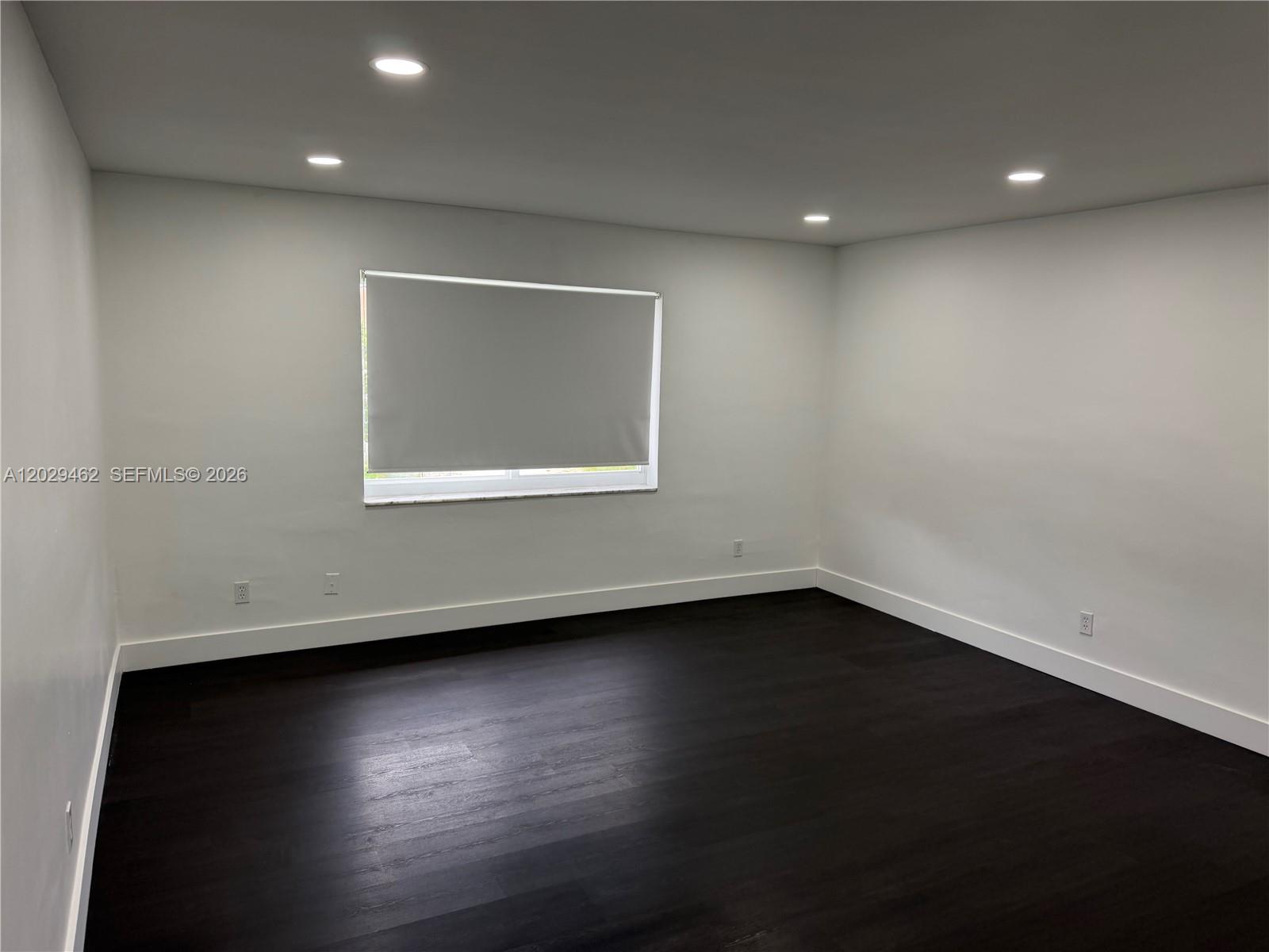 An empty room features white walls, dark wood flooring, recessed lighting, and a single window — 4850 SW 26th Ave # 4, Dania Beach FL 33312, DANIA BEACH, FL